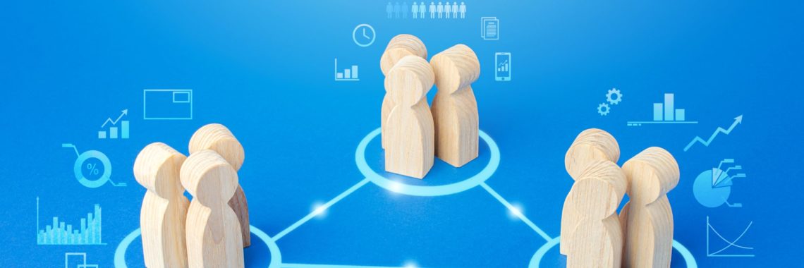Wooden block men positioned at the apexes of a triangle to represent partnership, consultancy and discussion.